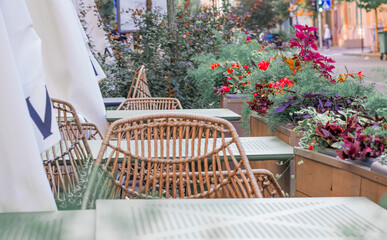 fancy patio cafe in outdoor street pedestrian space spring day time with furniture and blossom flowers in pots without people here