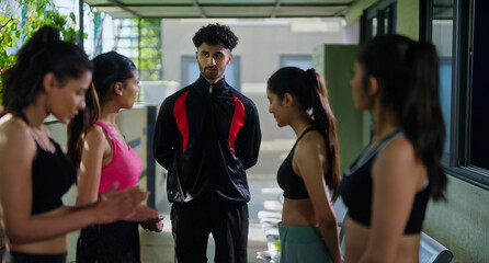Indian young adult gen z sports woman lady group team fit coach man talk speak share plan ideas day time at campus place male guy explain game to female girls player in break time indoor area