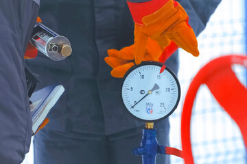 working oil operator screws a pressure gauge to a tap on a gas pipeline.