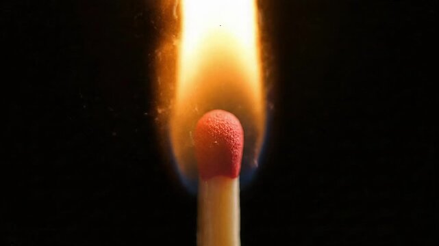Matchstick head igniting in ultra slow motion creating vibrant dancing flame against black background in abstract macro detail