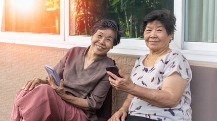 Asian elderly woman using a smartphone interacts with the screen or taking selfie reflecting the growing connection between seniors and digital technology.