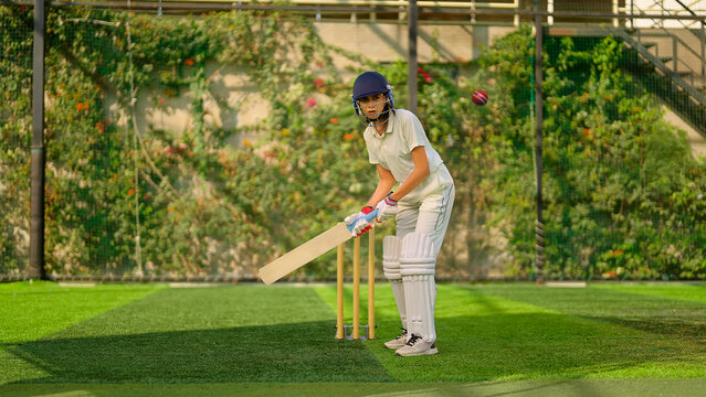 Indian young adult gen z sports woman lady standing hold bat play learn cricket match do practice to hit ball at garden angry teen female girl player wear white uniform leg guard hand gloves day time