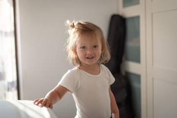 Fototapeta premium Happy Little Toddler Smiling Indoors in Natural Morning Light. Cute Child with Messy Hair at Home, Joyful Childhood Moment, Warm Family Lifestyle Photography