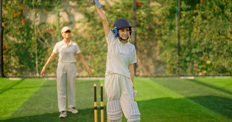  Indian gen z young adult woman lady wear hand gloves white dress leg guard helmet day time cricket player sports teen female girl hold bat play casual match game hit ball do batting at ground place