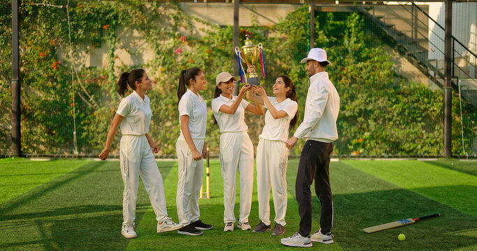 Indian asian young adult gen z sports woman lady group team standing with coach man win cricket match trophy do celebrate outdoor male trainer female player cheering having fun joy outside play ground