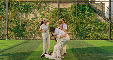 Indian young adult gen z sports woman lady group win match held award in hand raise up enjoy day time happy female team cheering have fun joy do hug shout loud scream yes at play ground place