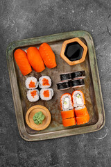 A vibrant assortment of fresh sushi, including nigiri, rolls, and sashimi on grey background top view vertical photo
