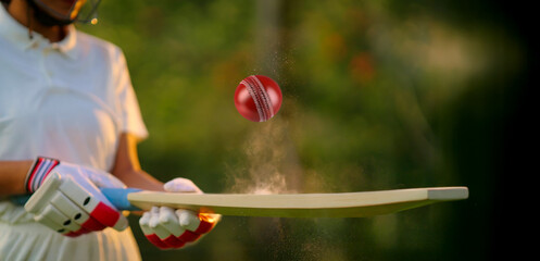 unknown athlete sports woman hand close up hold bat play with red ball outdoor ground. female girl cricket player wear white uniform protective helmet gloves standing at match playground