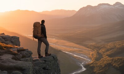Obraz premium Man with backpack on mountain cliff at sunrise
