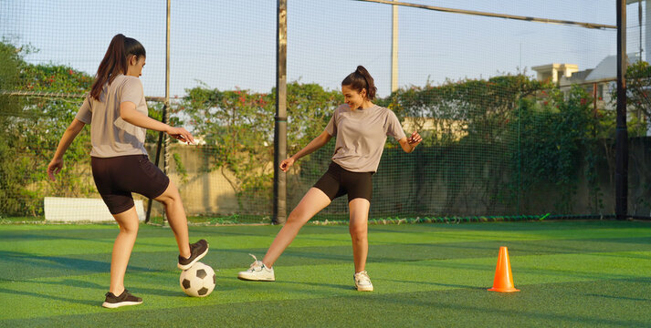 Indian asian happy young adult gen z girl group of sports woman playing football outdoor yard smiling female lady players game kicking soccer ball team have fun joy outside ground place - Powered by Adobe