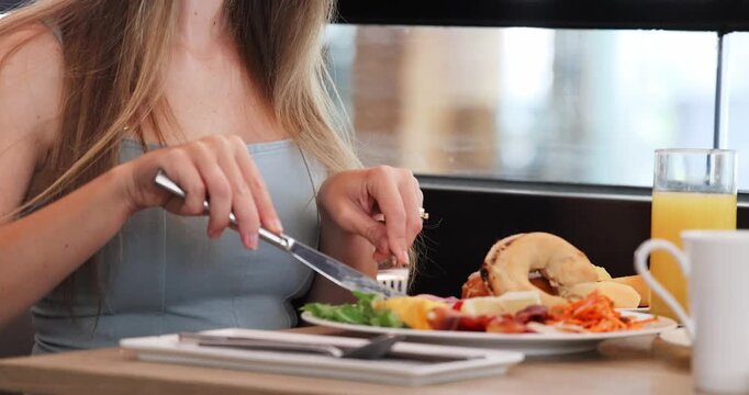 Woman enjoying healthy breakfast at modern cafe, featuring fresh bagels, salad, juice. Casual dining, healthy lifestyle, vibrant morning scene.