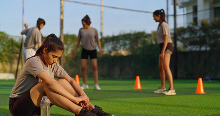 Indian young adult woman lady group team play football enjoy day have fun joy outdoor place tired upset sad gen z female girl player sitting on ground take rest time relax break after sport game