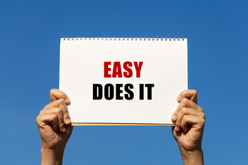 Easy does it text on paper holding by a woman's hand with blue sky background
