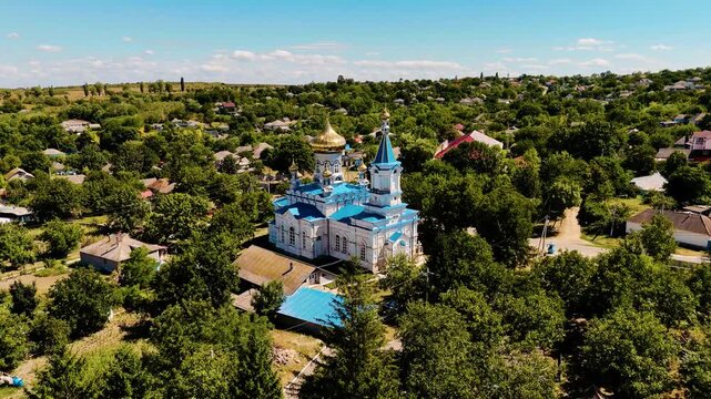 Aerial View of Moldovan Village with Blue and Gold Orthodox Church Surrounded by Lush Greenery