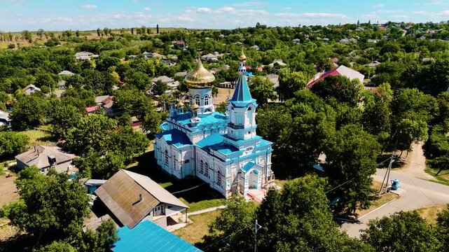 Aerial View of Moldovan Village with Blue and Gold Orthodox Church Surrounded by Lush Greenery