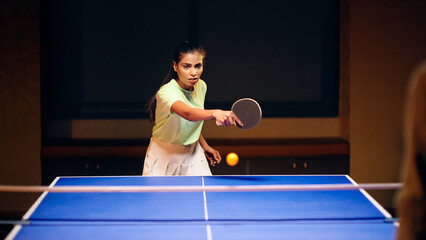 Indian happy young adult gen z athlete player woman hold racket play table tennis passing ball...