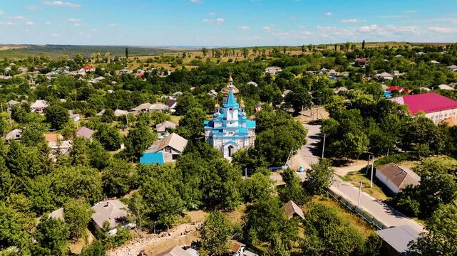 Aerial View of Moldovan Village with Blue and Gold Orthodox Church Surrounded by Lush Greenery