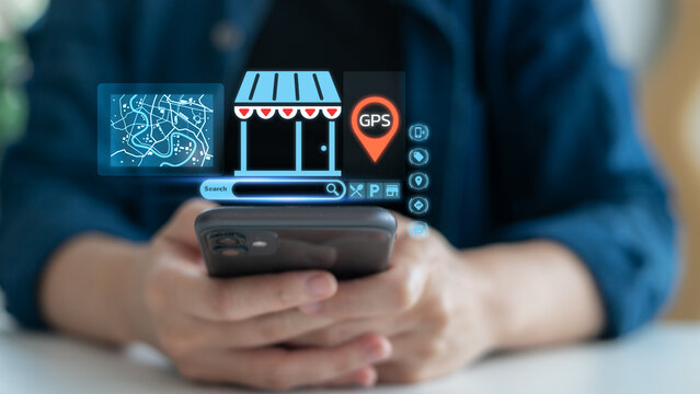 Hand holding a smartphone with hologram GPS navigation, map, and local business search icons. Concept of mobile map app, online store location, digital marketing, and smart navigation technology. - Powered by Adobe