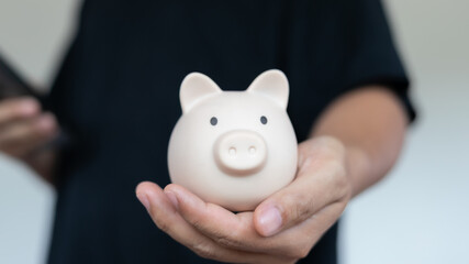 Close-up hand holding a piggy bank. Concept of saving money, personal finance, investment, banking,...