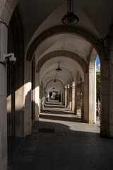 Long arcade with columns and lamps casting shadows in merida, spain