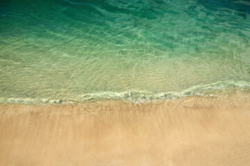 Tranquil Shoreline. A serene beach with clear green water and golden sand