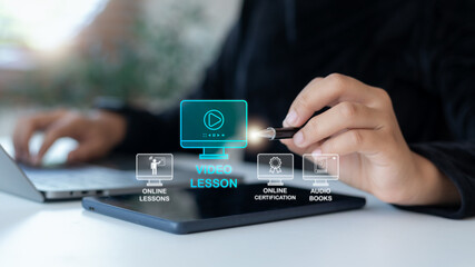 Hand using a tablet with hologram icons of video lessons, online certification, and audiobooks. Concept of digital education, e-learning platform, online study, and modern learning technology.
