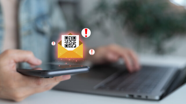 Close-up hand holding a smartphone with a hologram phishing email and QR code scam alert. Concept of cybersecurity, online fraud, phishing attack, data protection, spam risk, and IT security.