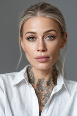Portrait of a woman with platinum blonde hair and striking green eyes, showcasing intricate tattoos against a neutral background