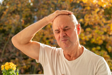 mature man suffering from severe migraine, holding head in pain, pained expression, migraine...