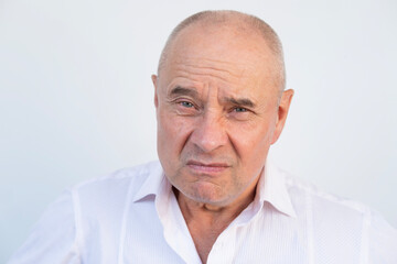 Angry older man with furrowed brow, intense gaze, and pursed lips. Serious senior man looking aggressive and upset, expressing strong emotions, Concept aggression, tension, and confrontation