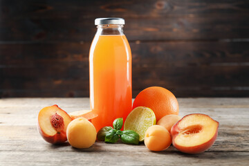 Tasty juice in glass bottle, fresh ingredients and basil on wooden table against brown background, closeup