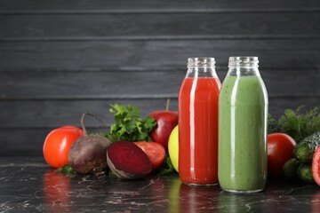 Tasty juices in glass bottles and ingredients on black marble table