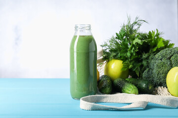 Tasty juice in glass bottle and ingredients on light blue wooden table, closeup. Space for text