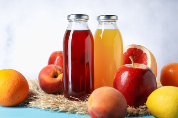Tasty juice in glass bottle and fresh fruits on light blue wooden table, closeup