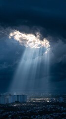 Sunlight streams through a break in the clouds, illuminating a city below with dramatic light.