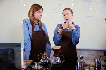 young barista woman making fresh coffee from machine and checking quality in the cafe