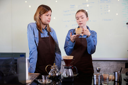 young barista woman making fresh coffee from machine and checking quality in the cafe