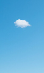 A single fluffy white cumulus cloud floating alone in a vast clear blue sky, a concept of minimalism and tranquility