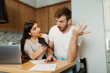 Obraz premium Couple checking bills at home with calculator and laptop, managing family finances and expenses together