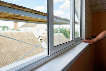 Installing metal-plastic window on a balcony in a house.
