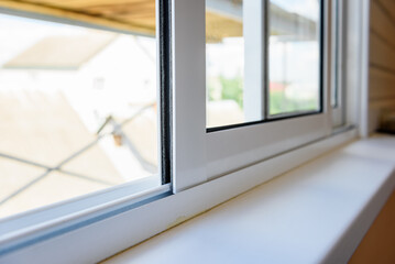 Hand opening white plastic sliding window on balcony.