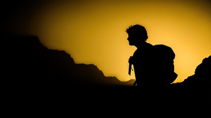 A mountain climber gazes at a distant peak, silhouetted against a golden sunrise in a dramatic landscape.