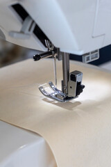 Close-up view of a modern sewing machine with its presser foot, needle, and thread preparing to stitch light fabric. This image emphasizes precision and craftsmanship in textile work.