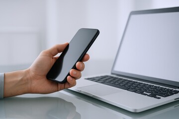 Person Holding Smartphone Near Laptop, Modern Workspace Technology for Business, Communication and Productivity