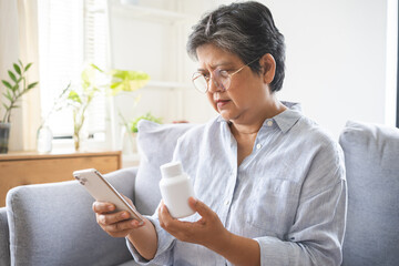 Health care concept, asian senior woman using smart phone reading, searching prescription on bottle medicine, pill label text about information online, instructions side effects, pharmacy medicament.