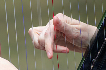 Close up of a female hand plucking the strings of a harp