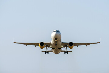 Passenger jet nearing runway, landing gear extended, illuminated landing lights signaling imminent touchdown during approach