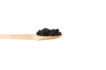 Dried Aronia or black chokeberry - Aronia melanocarpa in latin on wooden spoon isolated on white background.