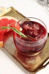 Tasty cocktail with grapefruit, ice cubes and rosemary on white table, closeup