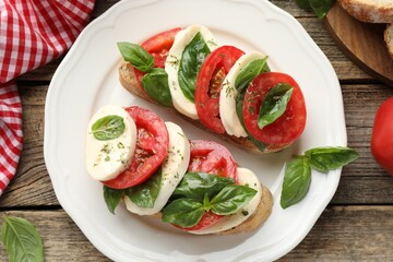 Delicious sandwiches with mozzarella cheese, tomatoes and basil on wooden table, flat lay